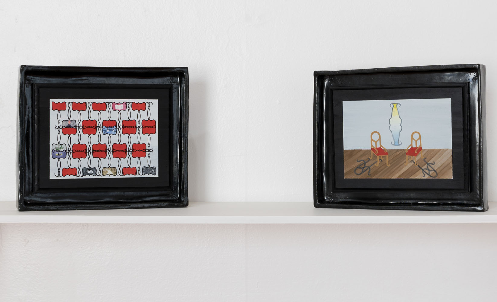 Two paintings with intricately worked geometric patterns in irregular dark and glossy frames on a white shelf.